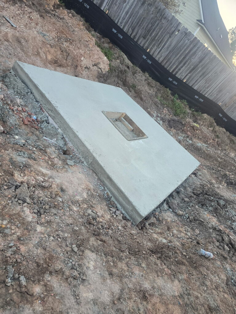 Small reinforced concrete equipment pad poured beside a building